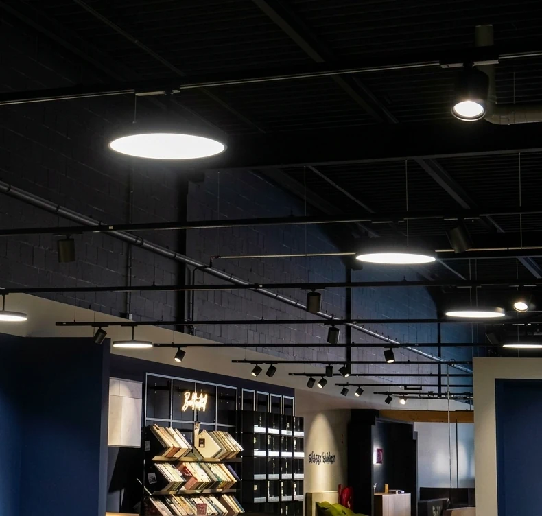 Fera 3-phase track luminaires in black above a bookshop interior, mounted on a 3-phase track system